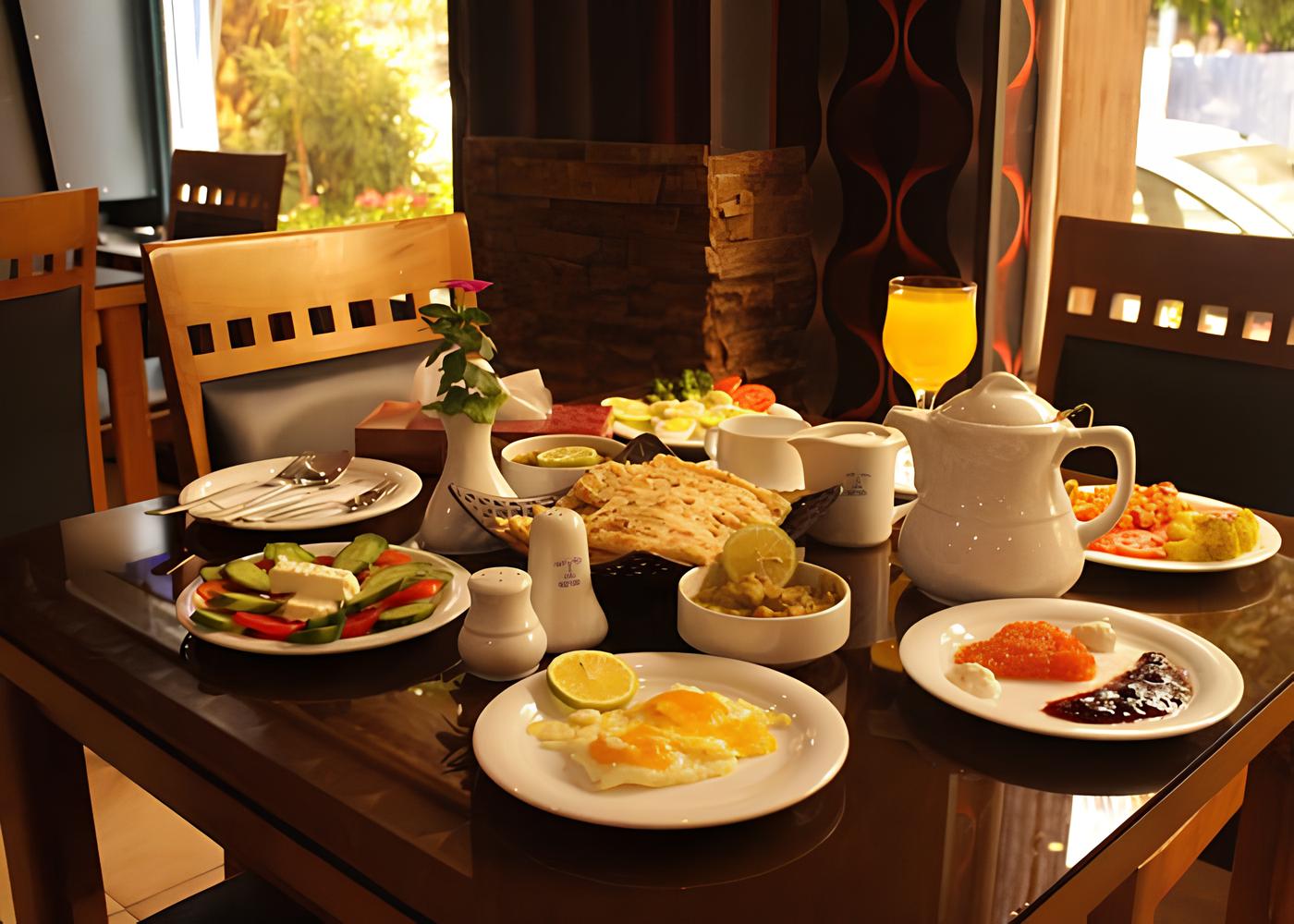 میز صبحانه هتل تالار با بشقاب‌های متنوع غذا